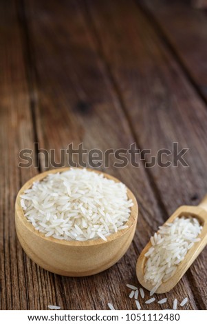 White rice (Thai Jasmine rice) in woodenspoon on wooden backgrou