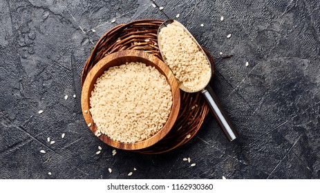 White rice in wooden bowl on black background. Top view of grains. - Powered by Shutterstock