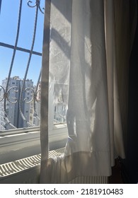 White Ripped Curtain Torn In Front Of A Window With Black Metal Grate