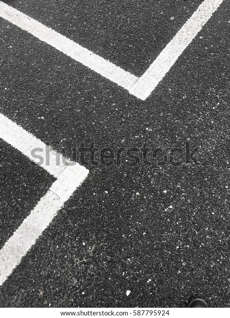 White road marking lines over dark\
gray urban asphalt pavement, vacant parking lot\
places