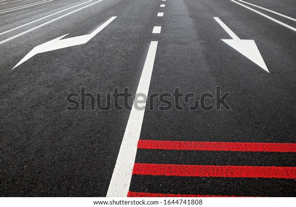 White road marking lines and red rumble strips on\
the road. Arrows on the road.\
