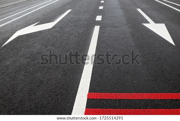 White road marking lines and red rumble strips on\
the road. Arrows on the road.\
