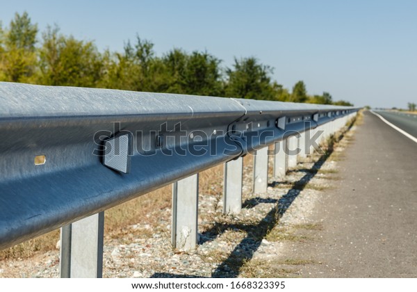 white road reflectors along the\
road. metal road fencing of barrier type. Road and traffic\
safety.