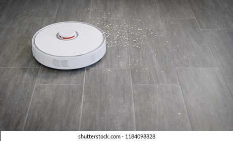 White Robot Vacuum Cleaner Device Cleaning Floor From Crumbs At Home