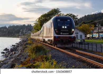 White Rock, British Columbia, Canada - September 9, 2019: Train passing by the Pier during a cloudy summer sunset.