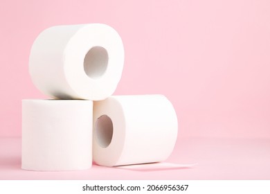 White rolls of toilet paper on pink background