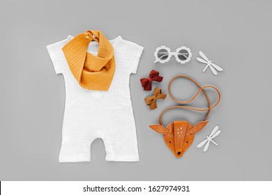 White Romper, Orange Bib With Kids Handbag And Sunglasses. Set Of  Baby Clothes And Accessories For Summer Vacation On  Gray Background. Fashion Childs Outfit. Flat Lay, Top View