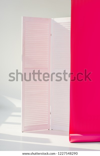 white\
room divider with bright pink rolled out\
wallpaper