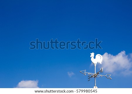White rooster weather vane show the wind direction on blue sky background