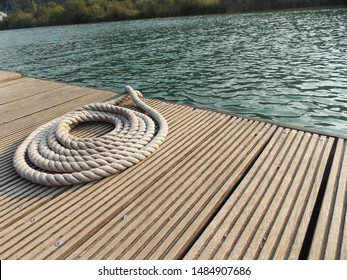 White rope on a wooden dock. It is used for securing docks and lines from boats. - Shutterstock ID 1484907686
