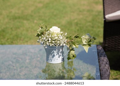 White rose and baby's breath centerpiece sitting on glass table at outdoor wedding reception - Powered by Shutterstock