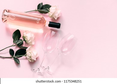 White Roses, Wine And Glasses For Wine On A Soft Light Pink On Wood Table. Flat Lay, Top View, Copy Space