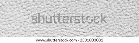 White rough plaster facade with rough bumpy surface in panoramic close-up