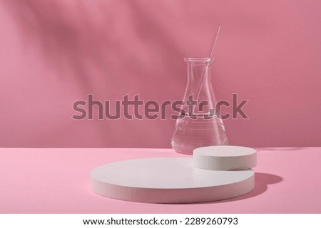 White round empty podiums for cosmetics product presentation and erlenmeyer flask containing colorless liquid on pink background. Science laboratory research and development concept