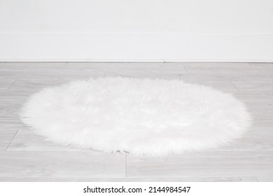White round fluffy rug carpet lying on floor by white wall at home. Background mockup for designs and backdrop.