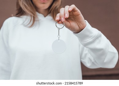 White round keychain mockup in woman's hand. Blank white sublimation keychain. Copy space.