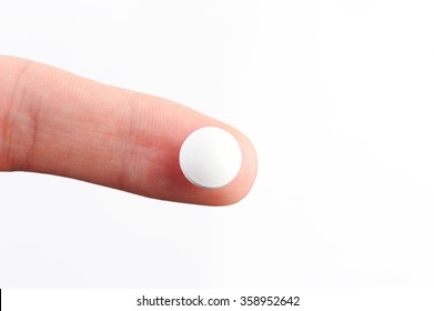 White Round Pill Lay On Finger On White Background