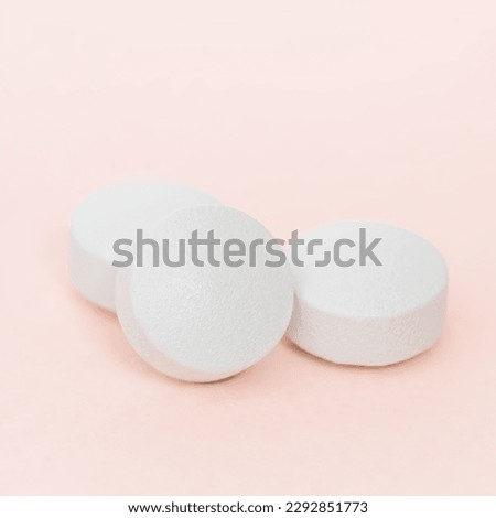 White round pills on pink background. A heap of small round meds close up. Health care and medicine concept.
