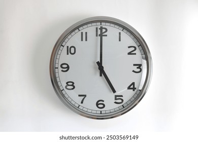 A white round shape wall clock with black hands showing the time of 5 o'clock cutout from background. Short hand at 5 o'clock and long hand at number 12.
