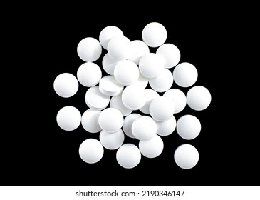 White round small pills on a black background, heap, top view, macro - Shutterstock ID 2190346147