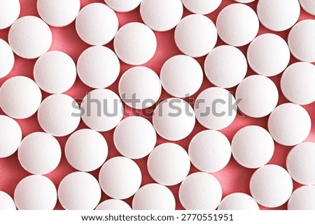 White round tablets pattern on pink background. Pharmaceutical medicine concept. Prescription pills flat lay scene. Healthcare treatment backdrop. Pharmacy dosage closeup. Medical wellness product