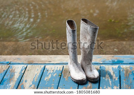 White, rubber, Shrimper boots, on a wooden porch, during Hurricane Laura, with rising floodwater in the background, located off the coast of South Louisiana.