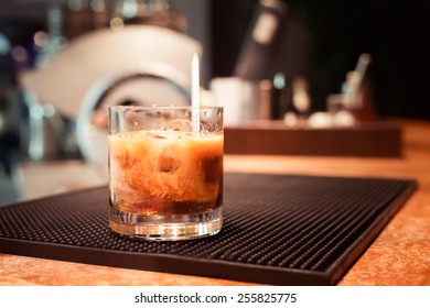 White Russian Cocktail On The Bar Stand On Rubber Mat. Shallow DOF And Marsala Tonned