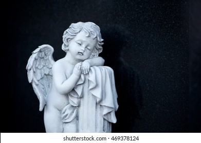 White sad angel on black background isolated.