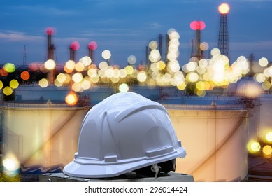 white safety helmet standing in front of oil refinery background