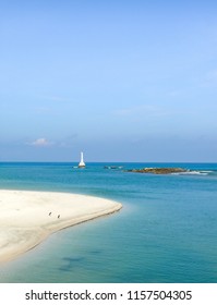 White sand beach, blue sea and lighthouse in the sea