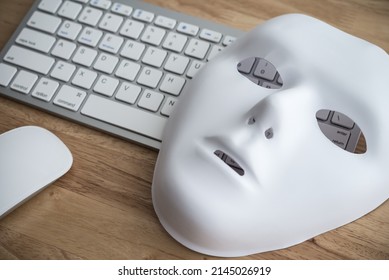 White Scary Half Face Mask, Keyboard And Mouse On Wooden Table Background In Dark Tone. Hacker, Cybercrime, Romance Scam And Online Security Concept.