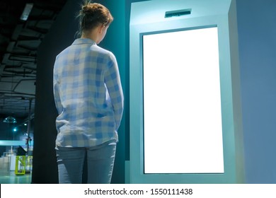 White screen, mock up, future, copyspace, template, isolated, technology concept. Woman looking at blank interactive touchscreen white display of electronic kiosk at futuristic exhibition or museum