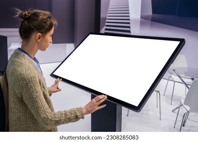 White screen, mock up, future, copyspace, template, technology concept. Woman looking at blank interactive touchscreen white display of electronic kiosk at futuristic exhibition or museum