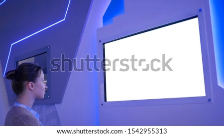 White screen, mock up, future, copyspace, template, isolated, technology concept. Woman looking at blank digital interactive white display wall at exhibition or museum with futuristic scifi interior