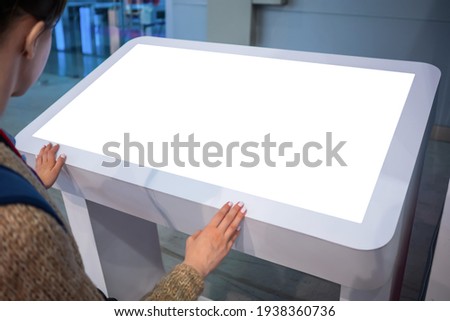 White screen, mock up, future, copyspace, template, technology concept. Woman looking at blank interactive touchscreen white display of electronic kiosk at futuristic exhibition or museum