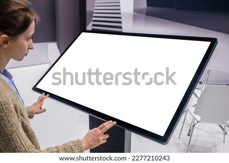 White screen, mock up, future, copyspace, template, technology concept. Woman looking at blank interactive touchscreen white display of electronic kiosk at futuristic exhibition or museum