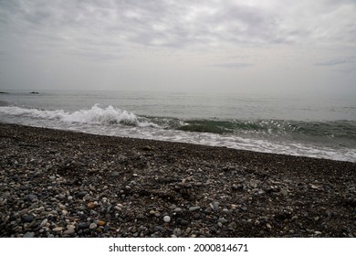 White Sea Foam On A Rocky Pebble Beach, High Tide, Storm