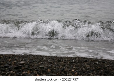 White Sea Foam On A Rocky Pebble Beach, High Tide, Storm