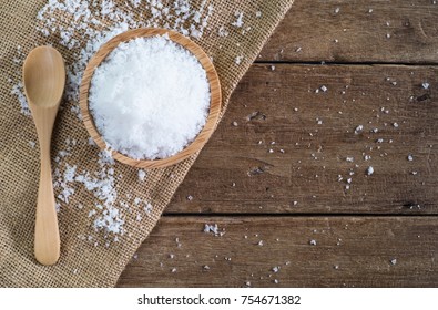 White Sea Salt In Wood Bowl With Wood Spoon On Gunny Sack Cloth On Brown Wooden Table, Top View With Copy Space