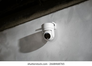 A white security camera is mounted on a wall, providing a sleek and modern observation solution for enhanced safety and monitoring in both indoor and outdoor settings.