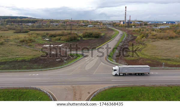 White semi truck\
driving on empty road, transporting goods on sunny day. Freight\
container truck hauling and delivering cargo across a country.\
Trucking logistics\
shipping
