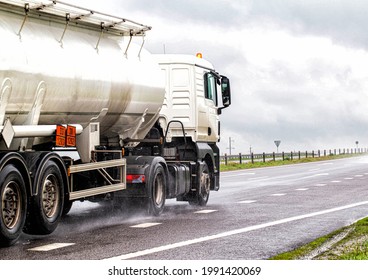 A white semitrailer tractor with a stainless tanker truck transports dangerous goods on the road. Kotsnet transportation of engine oil and diesel fuel to filling stations. 