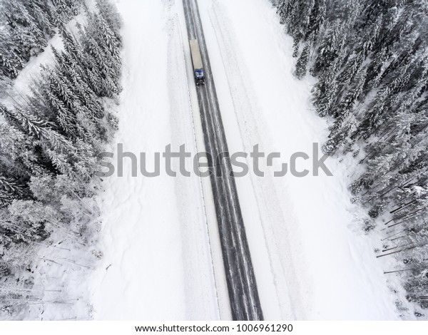 White semitrailer truck\
fast driving toward on slippery winter asphalt highway, aerial view\
from drone