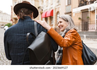 White Senior Couple Talking And Smiling At Camera While Walking At City Street