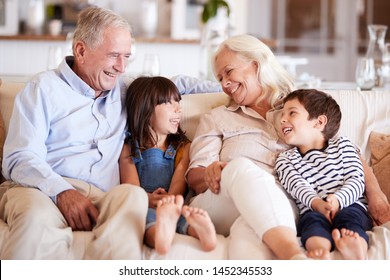 White senior couple and their grandchildren sitting on a sofa together smiling at each other