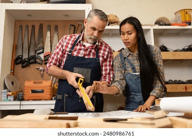 White senior man carpenter doing his work with Asian co worker woman, craft work at furniture factory and copy spcae. - Powered by Shutterstock