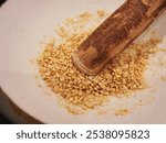 White sesame seeds in a Suribachi bowl with grinding stick on a wooden table . These are usually served in Japanese ramen restaurant