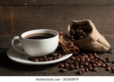 A white set of coffee on wooden and sacking background with cinnamon and coffee beans
