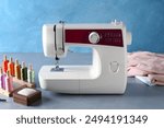 White sewing machine and craft accessories on gray table near light blue wall