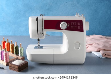 White sewing machine and craft accessories on gray table near light blue wall